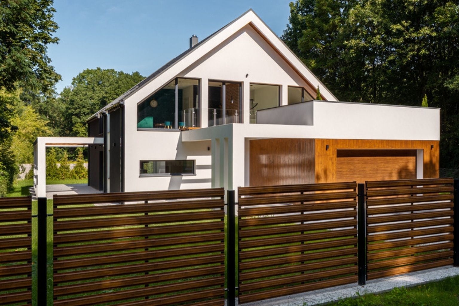 Moderne hus med mørkt lamelhegn og græsplæne